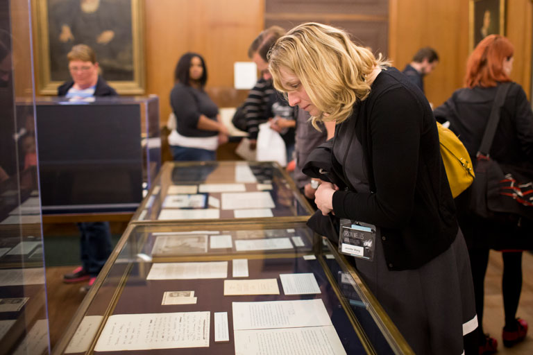 A woman looks at documents on display in a glass case at the Lilly Library.