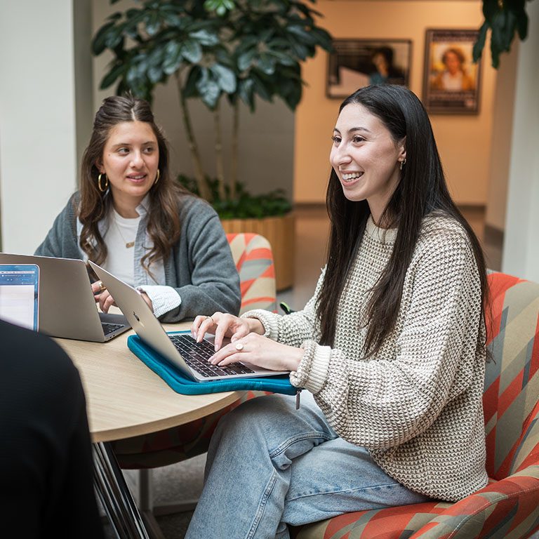 a small group of students work together on their laptops at a table