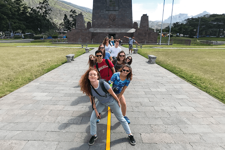 a group of students straddle a yellow line marking the equator