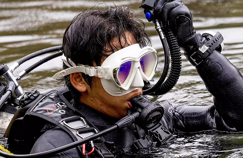 Male wearing diving gear in the waters of a lake.