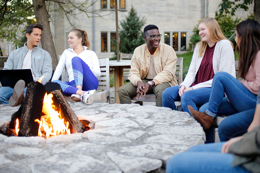 Students gathered around a fire pit in front of the IMU building.