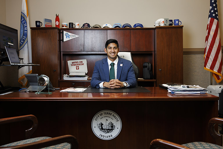 A person in a suit sits behind a desk. The desk has a seal that says ‘City of Terre Haute, Indiana.’