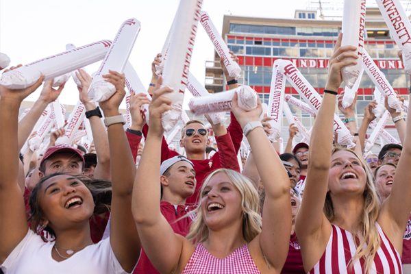 Female students at an event cheering and holding noise makers.